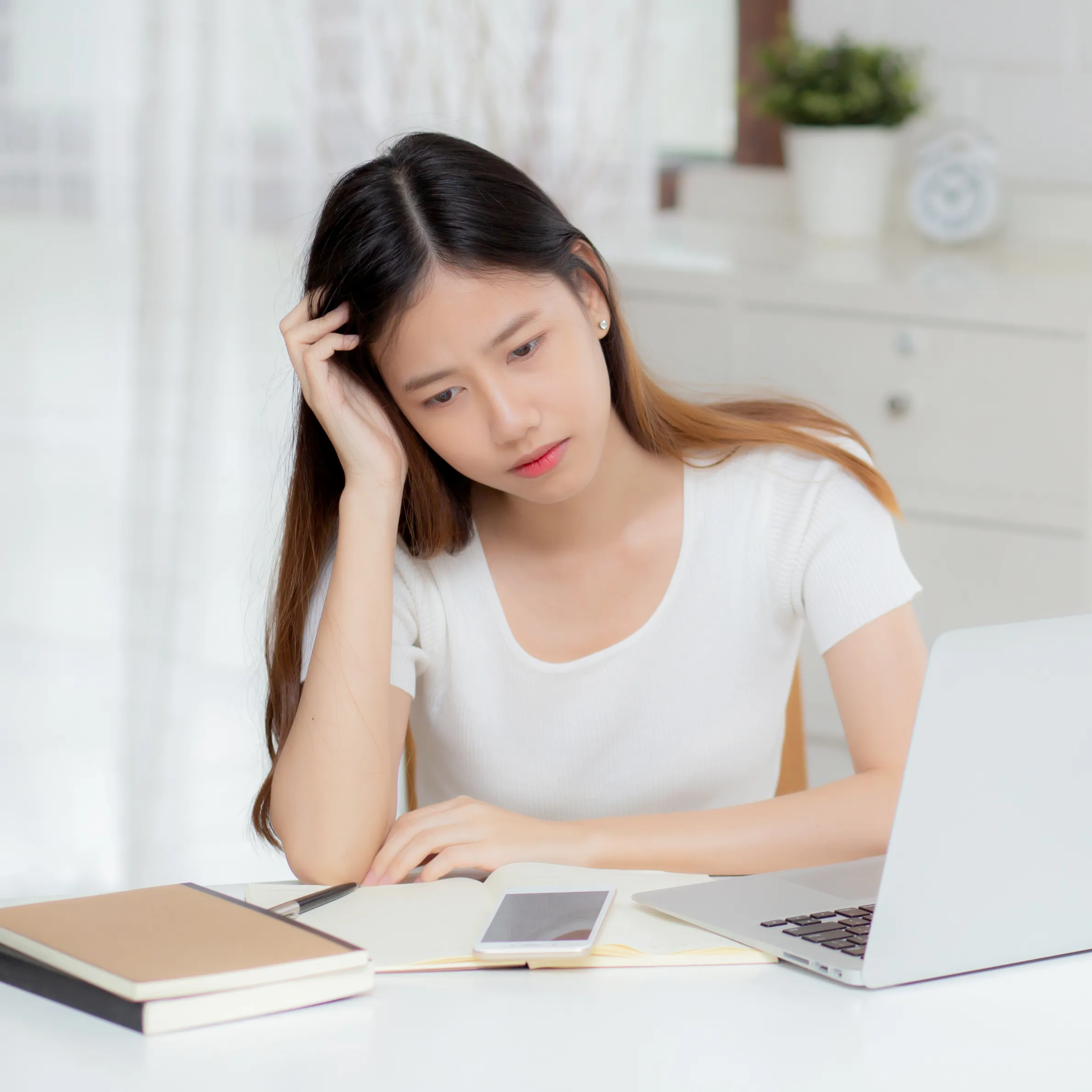 ノートパソコンの前で悩む女性の写真