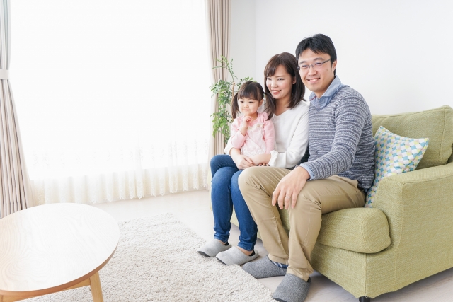 ソファに座って笑顔で過ごす家族の写真