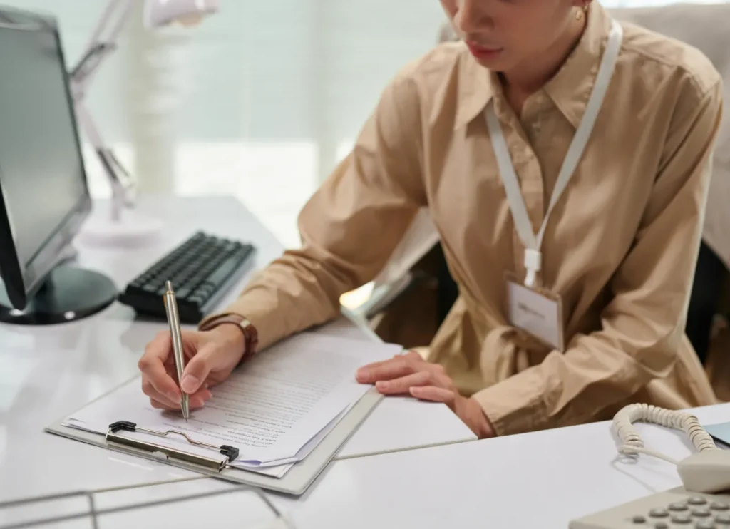 書類に記入するビジネスウーマンの写真。住宅ローン救済センターが実績に基づき最適な金融機関を選定する様子を表現している。